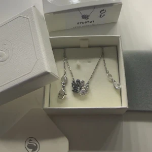 Silverfärgat halsband från Swarovski - Säljer ett elegant halsband från Swarovski i silverfärg med två svanar.  Perfekt för att ge en extra touch till din outfit.