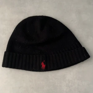Svart stickad mössa från Polo Ralph Lauren  - Snygg polo mössa som har växt ur mig bra skick dock inget kvitto