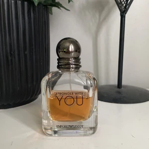 Byttes mot skor helst  - En elegant herrparfym från Emporio Armani, Stronger With You. Flaskan är genomskinlig med rundade kanter och har en silverfärgad metallkork. Doften är varm och modern, perfekt för dig som gillar stilrena och maskulina toner.
