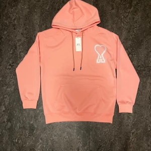 Ami Paris hoodie  - Säljer en rosa hoodie från Ami Paris med vit broderi hjärta. Den är lite liten i storlek. 