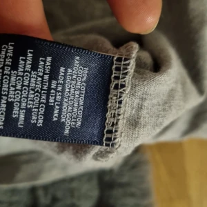 Grå t-shirt från Polo Ralph Lauren - Säljer en klassisk grå t-shirt från Polo Ralph Lauren med broderad svart logga på bröstet. Tröjan är i mjuk bomull och har rund halsringning och korta ärmar. Perfekt basic-plagg till garderoben.