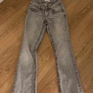 Grå low waist bootcut jeans från ginatricot - Säljer ett par grå low waisted bootcut jeans från Gina. Endast använda 1 gång då jag inte gillar mig själv i grått. Ser helt nya ut, inga fläckar eller hål såklart. 
