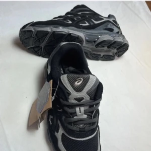 Asics gel nyc - Säljer ett par svarta och grå Asics sneakers med snygg sportig design. Skorna har meshdetaljer för bra ventilation, kraftig sula och snörning framtill. Perfekta för träning eller vardagsstil. Märkeslogga på sidan och plös. Priset är inte hugget i sten och kom med byten!✅✅