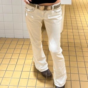 Vita bootcut jeans med nitar från LA Idol USA - Säljer ett par vita bootcut jeans från LA Idol USA med snygga nitar på fickorna fram och bak. Jeansen har låg midja och dekorativa detaljer. De är storlek 12 us men små i storleken. Skulle säga storlek 38/40🙌 Har vanligtvis storlek 36 men med bälte passar de bra. 
