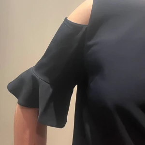 Marinblå klänning med volangärm från Zoul  - Säljer en marinblå klänning från Zoul i storlek S. Klänningen har offshoulder-design med volangdetaljer på ärmarna och en rak passform, slutar strax ovanför knät. Härligt tyg som faller fint. Använd ett fåtal gånger.