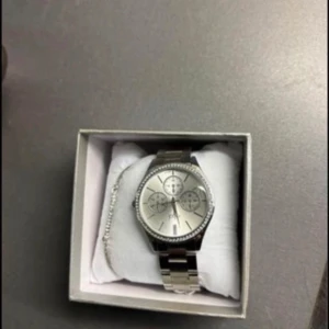 Silverfärgad klocka med länkarmband - Stilren klocka i silver med länkarmband och rund urtavla. Urtavlan har flera mindre visare och är dekorerad med stenar runt kanten. Perfekt accessoar för att lyfta din outfit.