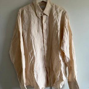 Beige linneskjorta från John Henric - Säljer en stilren beige skjorta i linne från John Henric. Skjortan har klassisk krage, knäppning framtill och långa ärmar. Perfekt för en avslappnad men ändå uppklädd look. Storlek 44 mycket bra skick. Nypris 999kr