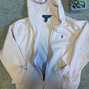Ljusrosa hoodie från Polo Ralph Lauren - Säljer min systers rosa Ralph Lauren zip up hoodie eftersom att den blivit för liten.  har knappast använts och har Inga defekter eller fläckar.  Storleken är i barnstorlek 12-14 L/G.  Hör av dig vid frågor eller funderingar!😊