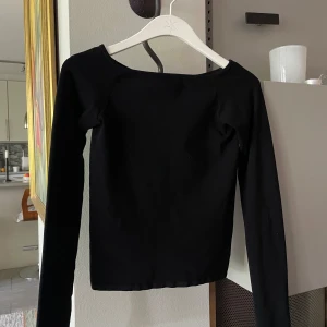 Svart långärmad topp från Weekday - En stretchig långärmad topp från Weekday med en lätt off-shoulder halsringning. Modellen är enkel och tight, perfekt att matcha med jeans eller kjol. Tillverkad i mjuk bomull som känns skön mot huden. 💕