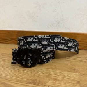 Svart och vit bälte i skinn - Snyggt bälte med svart och vit monogramdesign. Perfekt accessoar för att lyfta din outfit med lyxig känsla.