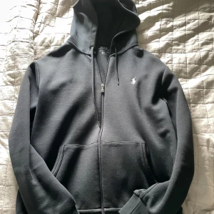  Polo Ralph Lauren zip hoodie - Svart hoodie från Polo Ralph Lauren. Perfekt för en chill och stilren look. Digitalt kvitto finns från johnells. Använd fåtal gånger
