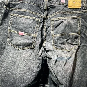 Svarta jeanssjorts Polo Assn, strl 34 midjan  - Säljer ett par svarta jeansshorts från U.S. Polo Assn. i klassisk femficksmodell. Shortsen har kontrastsömmar, logga på bakfickan och är tillverkade i slitstarkt denim. Perfekta för dig som gillar en avslappnad och tidlös stil.