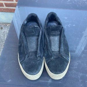 Svarta sneakers från Axel Arigato - Stilrena svarta sneakers från Axel Arigato i mocka med chunky vit sula. Slip-on modell utan snörning, perfekt för en clean och minimalistisk look. Passar till allt och ger en cool vibe till outfiten.