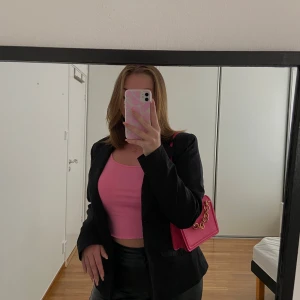 Rosa axelväska med guldkedja - Säljer en snygg axelväska i stark rosa färg med stilren, fyrkantig form. Väskan har en bred axelrem och en dekorativ guldfärgad kedja framtill. Materialet är slätt och känns som syntet. Perfekt storlek för det viktigaste och stängs med magnetknappar. Axelbandet kan skjusteras, använd en enstaka gång. Bra skick!🩷
