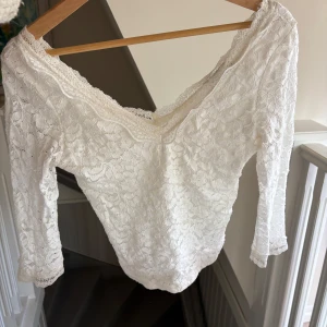Vit spetsblus från Bershka - Superfin vit blus från Bershka i spets med v-ringning och trekvartsärm. Blusen har ett romantiskt blommigt spetsmönster och är figurnära med snygg offshoulder-look. Den är i storlek m men sitter tajt så passar även s💗