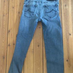 Jacob Cohën jeans - Snygga blå jeans från Jacob Cohën i klassisk modell med raka ben och fem fickor. Jeansen har en mellanblå tvätt, diskreta sömmar och patch med logga bak i midjan. Perfekta för en avslappnad och stilren look.