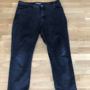 Mörkgrå jeans från Mingel, rak modell - Snygga mörkgråa jeans från Mingel i rak modell. Klassisk femficksdesign med bälteshällor och knapp med logga. Jeansen har en stilren look och passar perfekt till en avslappnad stil. Materialet är jeans och färgen är mörkgråa.