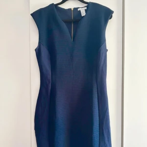 Marinblå klänning från H&M - Snygg marinblå klänning från H&M med ribbad struktur och markerad midja. Modellen är ärmlös med v-ringning och dragkedja i ryggen. Perfekt för dig som gillar stilrena och enkla plagg med en modern touch