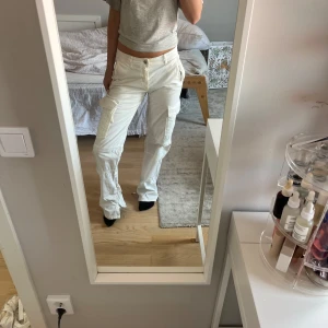 Vita cargopants med fickor - Jag säljer mina fina vita cargopants med flera  fickor på sidorna. Byxorna har låg midja och raka ben. Det är en storlek 32 men skulle säga att det passar en 34 också!