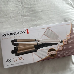 Remington ProLuxe 4-in-1 Waver - Remington ProLuxe 4-in-1 Adjustable Waver med snygg design i guld och vitt. Skapar fyra olika vågiga hårstilar med justerbar temperatur och OptiHeat-teknologi. Perfekt för dig som vill ha salongsvågor hemma. Lång sladd och digital display.