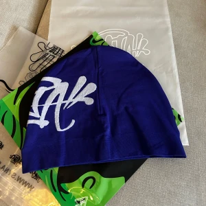 Syna World mössa i blå och svart - Två mössor från Syna World, Tunn, stretchig modell i mjuk bomull, helt nya, vid köp av en 599kr vid köp av två 1000kr