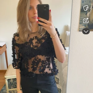 Svart blus med 3D-volanger från Gina Tricot - Supersnygg svart blus från Gina Tricot med transparent mesh och massor av 3D-volanger över hela toppen. 