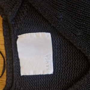 Randig stickad tröja från Sansa - Mörkblå stickad tröja från Sansa Collection med vita horisontella ränder. Tröjan har lång ärm och klassisk rund halsringning. Perfekt för dig som gillar en enkel men snygg stil med marint tema.