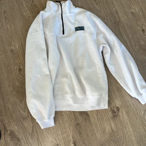 Vit fleece half zip från Junkyard XS - Supermjuk vit fleece-tröja från Junkyard i storlek XS. Tröjan har en hög krage och svart half zip-dragkedja framtill. Perfekt för kyliga dagar och har en relaxed passform med långa ärmar och ribbade muddar.