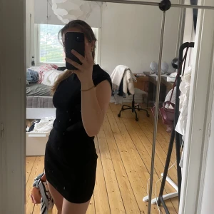 Svart tight kortklänning  - En svart, tight och enkel kortklänning i storlek XS. Klänningen är ärmlös med rund halsringning och har en figurnära passform som framhäver siluetten. Perfekt för dig som gillar minimalistisk och stilren look. Tjockare tyg