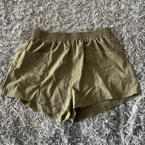 Olivgröna shorts från SHEIN  - Olivgröna shorts från SHEIN i storlek XL. De har elastisk midja, två stora fickor framtill och är tillverkade i ett lätt och svalt tyg, perfekt för varma dagar. Modellen är loose fit och passar skönt till sommaren.