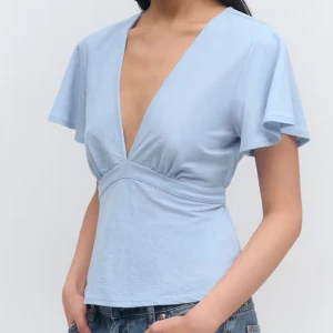 Ljusblå omlottopp med knyt - Supersöt ljusblå topp med djup v-ringning och korta, vida ärmar ifrån Gina Tricot! Passade tyvärr inte mig därav jag säljer den❣️