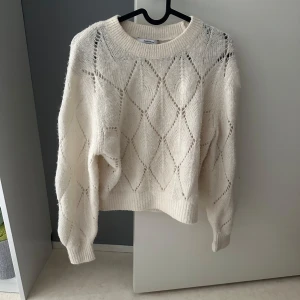 Vit stickad tröja & Other Stories XS - Superfin vit stickad tröja från & Other Stories i storlek XS. Tröjan har ett snyggt hålmönster i diamantform, rund hals och ribbade muddar. Materialet är en mjuk mix av alpacka och ull som gör den extra mysig och perfekt för kyliga dagar.