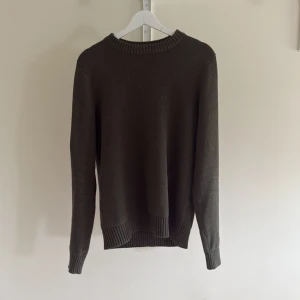 Mörkbrun stickad tröja från Dobber - En stilren mörkbrun stickad tröja från Dobber. Perfekt för lager-på-lager och passar till både jeans och chinos. Enkel design som funkar till det mesta. Den är knappt använd och funkar perfekt nu till sommaren. Hör av dig vid fler funderingar?