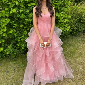 Rosa balklänning - Säljer en så fin lång, fluffig rosa klänning med flera lager volanger och v-ringad överdel. Jag är 175 men klänningen passar även kortare och längre, särkilt om man är kort med klack. Den här prinsessklänningen är perfekt för bal, student eller andra firanden! Köpt för 2400 och endast använt en gång 🩷 pris kan diskuteras ❣️storlek xs men passar även s
