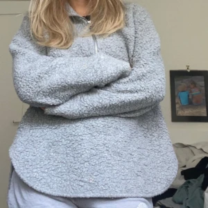 Grå fleece-tröja med half zip - Supermjuk och oversized grå fleece-tröja med halv dragkedja framtill. Tröjan har lång ärm och är tillverkad i fluffigt teddy-material som håller dig varm. Perfekt för kyliga dagar och chill outfits.