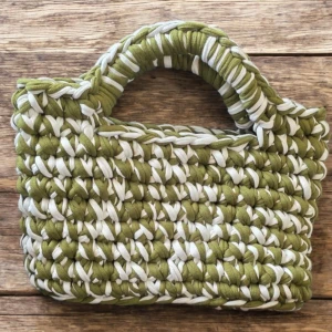 Handvirkad grön och vit handväska - Unik handväska i t-shirt virkat tyg med coolt mönster i olivgrönt och vitt. Väskan har rejäla handtag och en boxig form som gör den både snygg och praktisk. Perfekt för dig som vill sticka ut med en personlig accessoar.