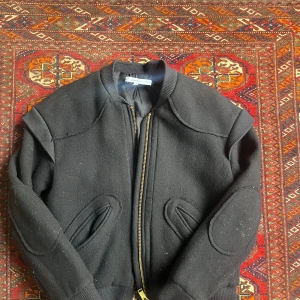 Mörkblå  bomberjacka från & Other Stories - Säljer en mörkblå bomberjacka från & Other Stories i storlek 36. Men enligt mig är den ganska liten så skulle säga strl 34! Jackan har coola detaljer som markerade sömmar, ribbade muddar och förstärkta armbågar. Stängs med en guldig dragkedja och har två snedställda fickor framtill. Perfekt för dig som gillar en stilren och edgy look.