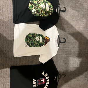 BAPE camo t-shirt svart och vit - Säljer BAPE t-shirts i svart och vit med ikoniskt camo-tryck av apans ansikte på bröstet. En av de svarta har även stort camo-tryck på ryggen. Klassisk passform, kortärmad och tillverkad i mjuk bomull. Perfekt för dig som gillar streetwear och vill sticka ut.