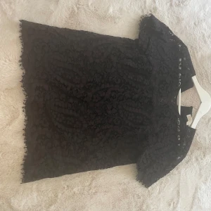 Svart spetsblus från Michael Kors - Supersnygg svart blus från Michael Kors i spets med korta ärmar och fina fransiga kanter. Blusen har en klassisk rund halsringning och ett elegant spetsmönster som ger en lyxig känsla. Perfekt för dig som vill sticka ut med en stilren och trendig look. Bara använd 2 gånger!  Nypris-1200kr 