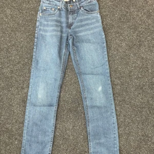 Levi's 512 Slim Taper jeans ljusblå - Storlek 12A.Snygga Levi's 512 Slim Taper jeans i ljusblå tvätt. Klassisk femficksmodell med smal passform och avsmalnande ben. Ikonisk läderpatch bak och röda Levi's-tag på bakfickan. Perfekta för en clean och stilren look.