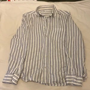 Randig skjorta från Zara i linne - Snygg vit linneskjorta från Zara. Skjortan är i luftigt och skönt linnematerial, storlek S, klassisk krage, bröstficka och knäppning framtill. Perfekt för en chill och stilren look.