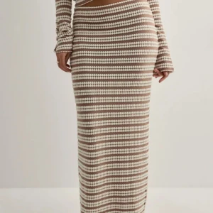 Beige och vit randig långkjol - Säljer en snygg långkjol med beige och vita ränder i stickad stil. Kjolen har en rak passform och är perfekt för dig som gillar en chill och trendig look. Superfin att matcha med en enkel topp eller stickad tröja. Aldrig använt, helt nytt. Säljer även matchande topp till kjolen i min profil!