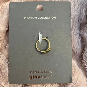 Grön blomring från Gina Tricot - Superfin ring i guldtonad stainless steel från Gina Tricot. Ringen har en grön blomformad detalj med små guldfärgade pärlor runt kanten. Perfekt statement piece för att lyfta din look.