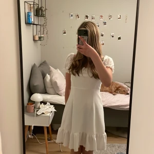 Vit kort klänning med puffärm och snörning - Superfin vit kort klänning med puffärmar och volangkant nertill. Klänningen har en snygg öppen rygg med snörning som ger en extra detalj. Perfekt för sommarens alla tillfällen och har en söt, feminin look. Klänningen är i st M men passar mig som bär S/xS pga knytet i ryggen. Säljer då den inte kommer till användning 💕