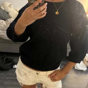 Svart stickad tröja med hålmönster - Snygg svart stickad tröja med hålmönster framtill. Tröjan har rund halsringning och trekvartsärmar som ger en chill vibe. Perfekt att styla med jeans eller kjol för en enkel men trendig look.