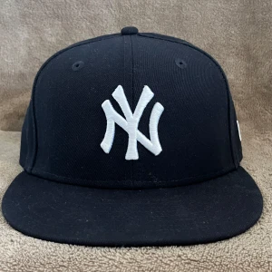 Svart New Era Yankees keps. Oanvänd köpt 8/6. Kvitto finns. - Klassisk svart New Era keps med New York Yankees logga broderad i vitt framtill. Kepsen har rak skärm och MLB-logga baktill. Tillverkad i bomull och polyester, perfekt för dig som gillar sportig streetstyle.