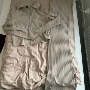Beige ribbade byxor från SHEIN - Säljer ett par beige ribbade byxor från SHEIN tillsammans med tröjan. Byxorna har en rak och loose passform med hög midja och är tillverkade i ett mjukt, stretchigt material. Perfekta för en avslappnad och trendig look. 