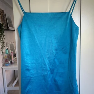 Blå klänning med smala axelband från MNG - Säljer en stilren blå klänning från MNG med smala axelband och rak passform. Klänningen har en enkel design och är perfekt för varma dagar. Färgen är klarblå och materialet känns mjukt mot huden.