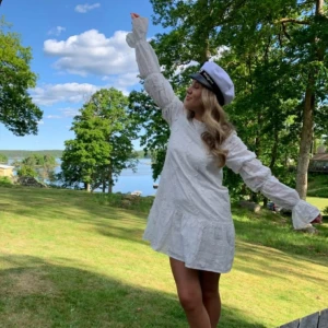 Studentklänning / vit kort klänning från NAKD - Jag säljer om en studentklänning jag köpte här på Plick, då jag valde att ha en annan istället. Den är bara använt en gång, och den har inga täcken på användning. Den har blomsterdetaljer, puffärmar och är djup i ryggen 😊. Skriv för fler bilder, och jag är villig att förhandla priset vid snabbt köp! 💗