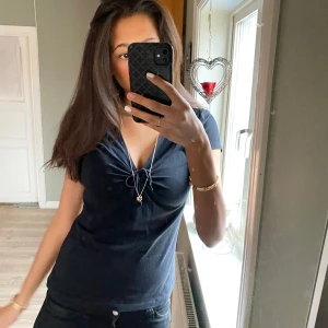 Svart v-ringad topp - Säljer en svart v-ringad topp med kort ärm och rynkdetalj framtill. 